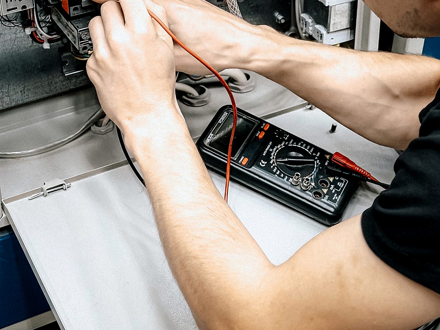 Electrician using a multimeter to test and diagnose an electrical panel